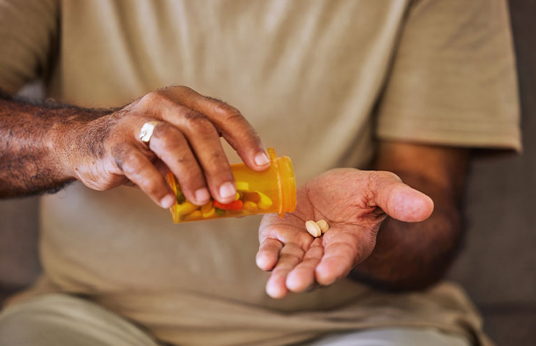 man putting pills in hand from bottle