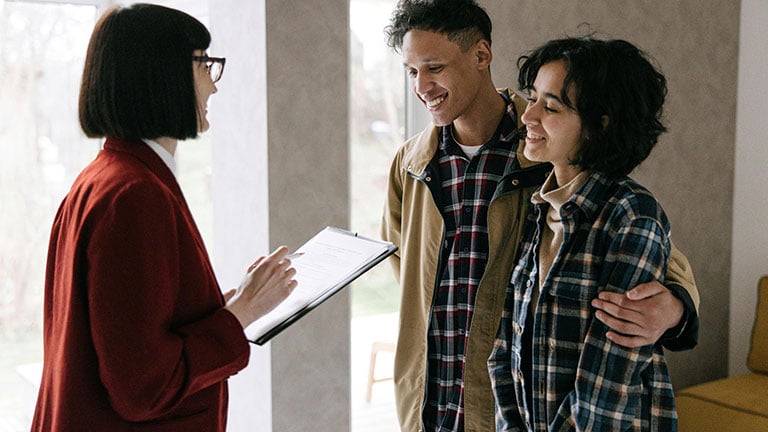 Woman Talking to the Couple While Holding a Clipboard Credit: Ivan Samkov with Pexels