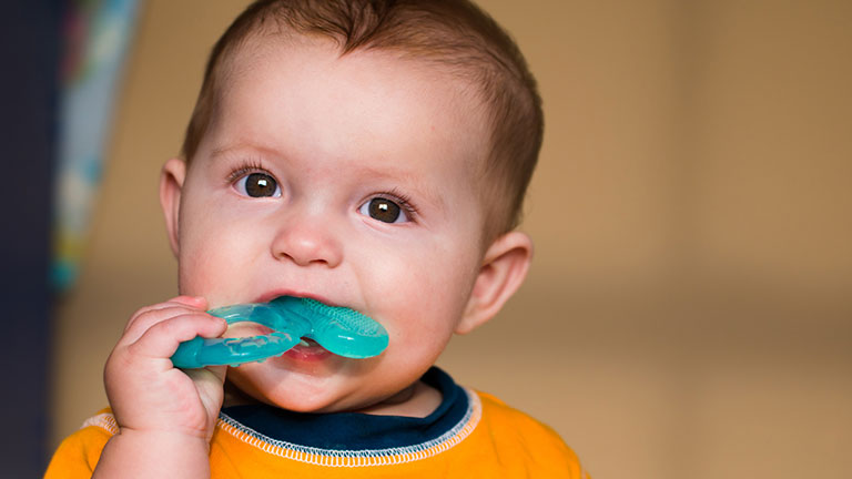Baby chewing on teething ring toy by Robert Hainer