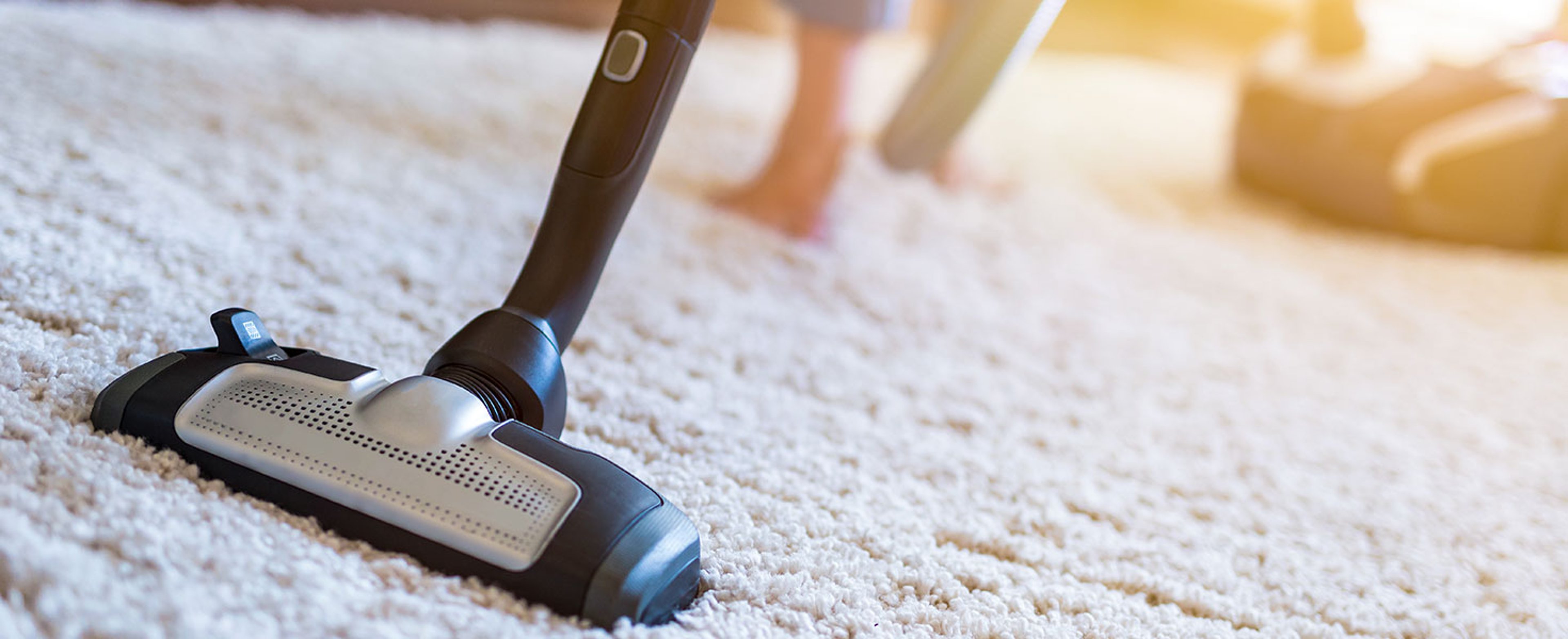 Woman using a vacuum cleaner while cleaning carpet in the house.  by REDPIXEL