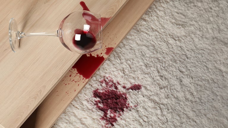 Overturned glass and spilled red wine on white carpet indoors, above view Credit: Liudmila Chernetska