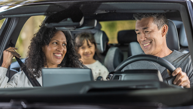 Cheerful family enjoying road trip in car. Credit: HappyKids