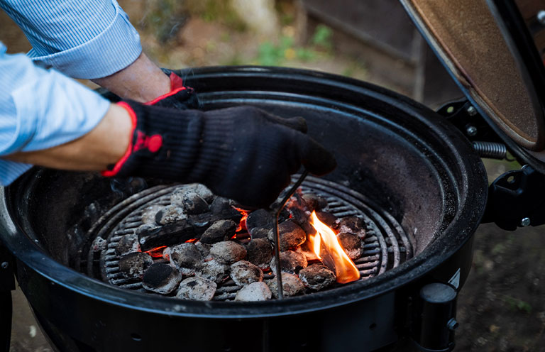 man with safety gloves starting grill