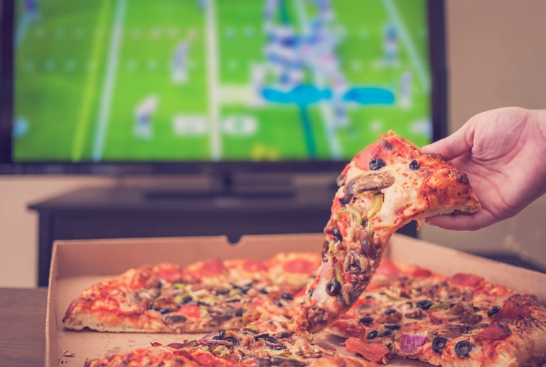 pizza in box with one slice being taken out, in front of nfl game on tv