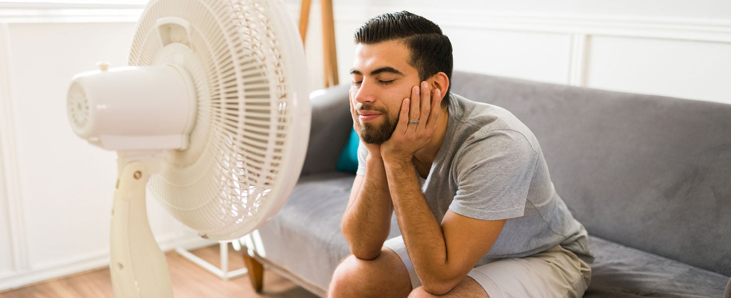guy sitting in front of fan