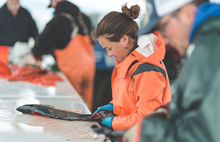 woman cleaning fish in warehouse