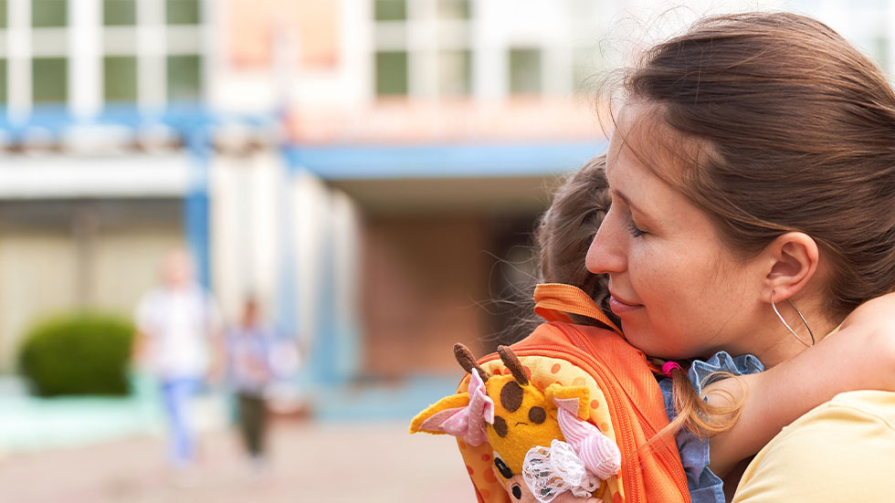 mom hugging kid in front of school