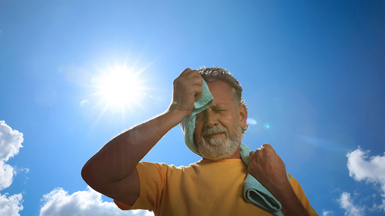 Senior man with towel suffering from heat stroke outdoors, low angle view Credit:Liudmila Chernetska