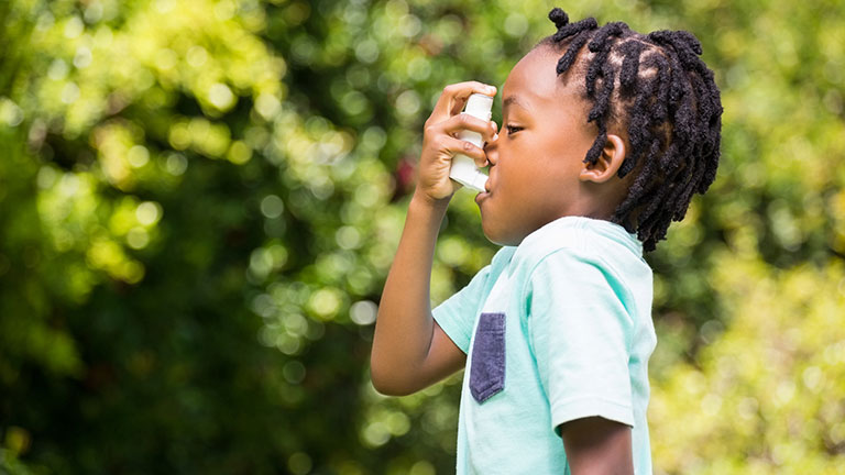 Boy using an asthma inhaler in the park Credit:Wavebreakmedia