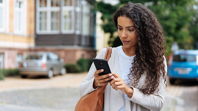 Young woman looking at her phone in consternation by contrastwerkstatt