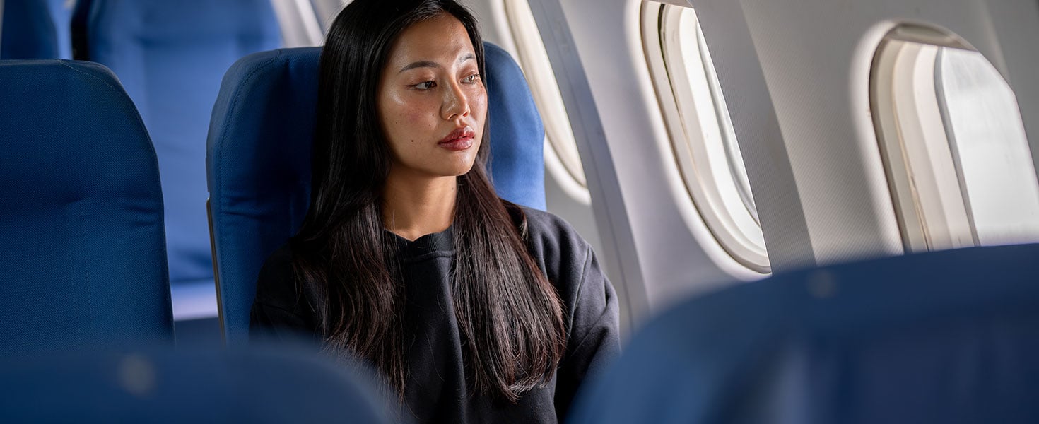 Thoughtful, lonely Asian woman travels alone on holiday, sitting on the flight with a sad expression  by bongkarn