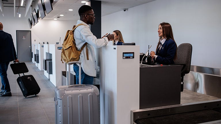 A young man checking in at an airport with his luggage Credit:miodrag ignjatovic