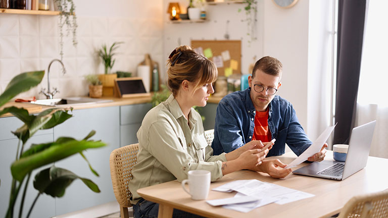 Young man and woman paying bills from home;  Credit: Anchiy