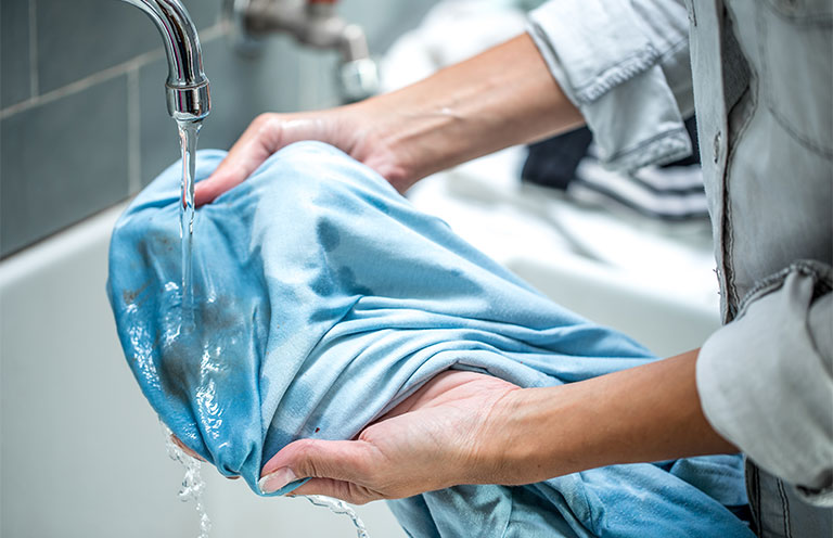 woman washing out stain on shirt