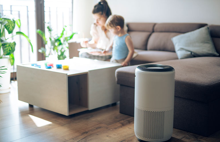 mom and child playing in background, air purifier in foreground