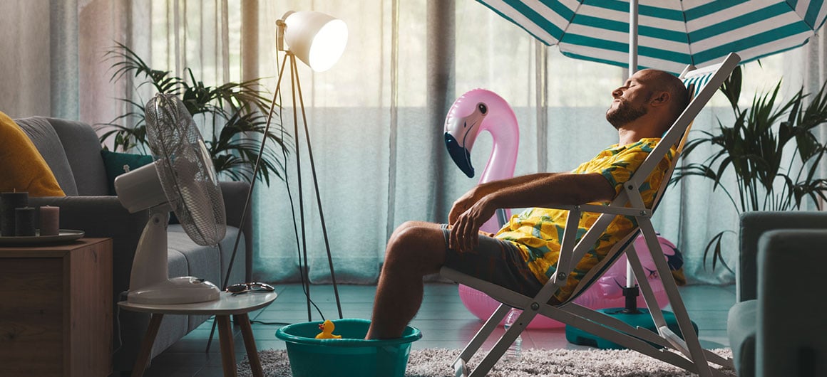 Bored man spending summer vacations at home and pretending he is on the beach, he is sunbathing in his living room and resting on a deckchair   Credit:demaerre 