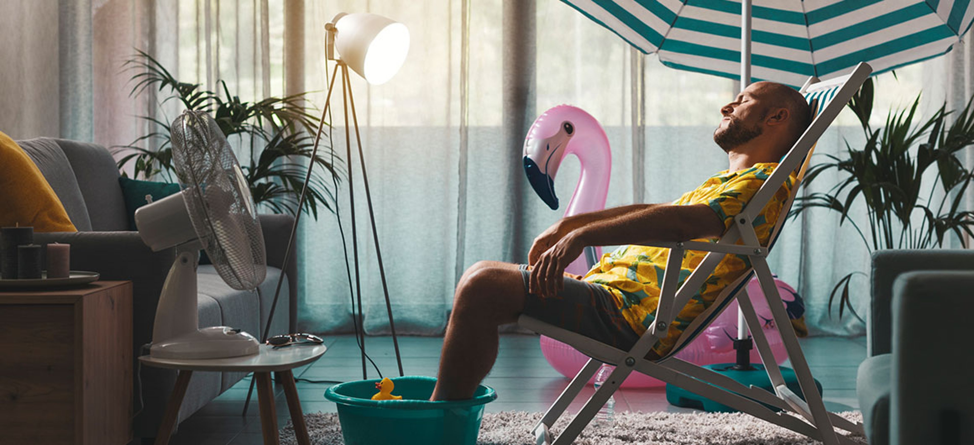 Bored man spending summer vacations at home and pretending he is on the beach, he is sunbathing in his living room and resting on a deckchair   Credit:demaerre 