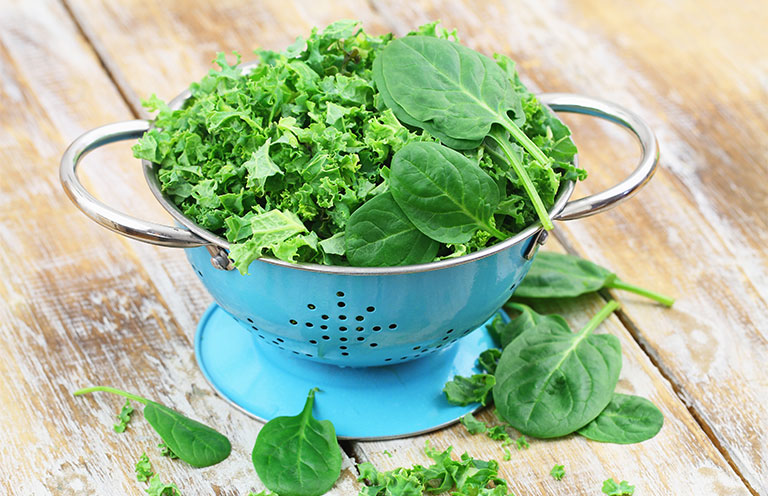 colander filled with green leafy vegetables 