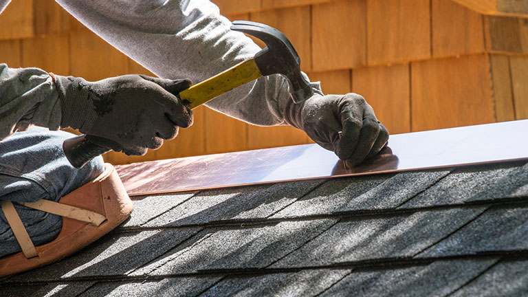 Installing new roof with hammer and copper edge flashing Credit: Bill Oxford