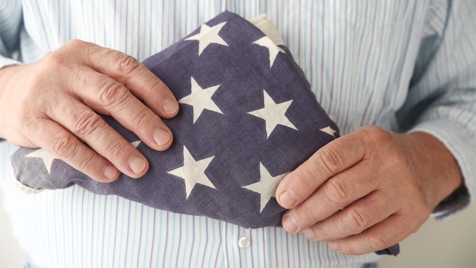 Man holding triangle folded American Flag