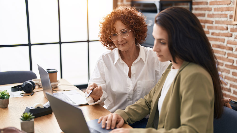 two women using laptops