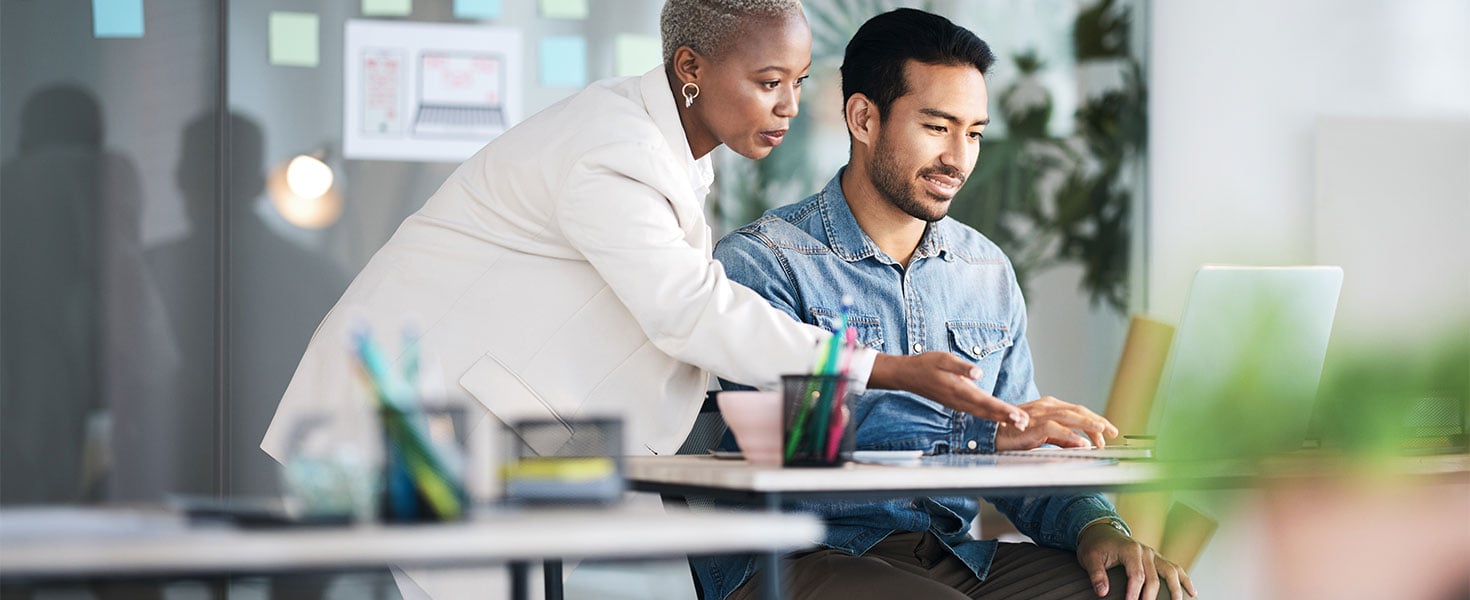 woman showing man something on laptop