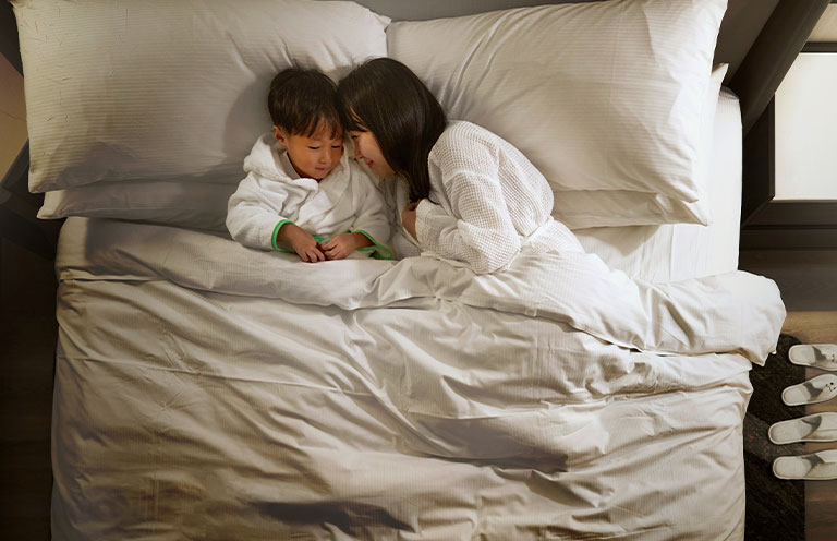 hilton hotel bedding, mom and son laying in bed