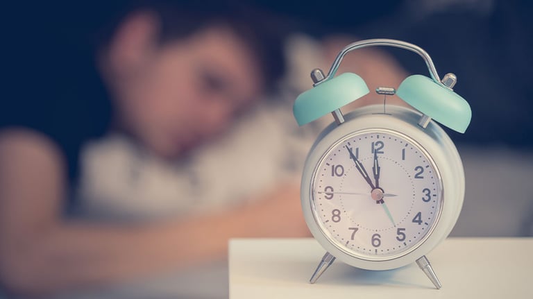 alarm clock with man sleeping in background