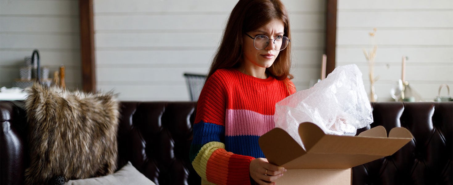Woman looking dissatisfied opening package