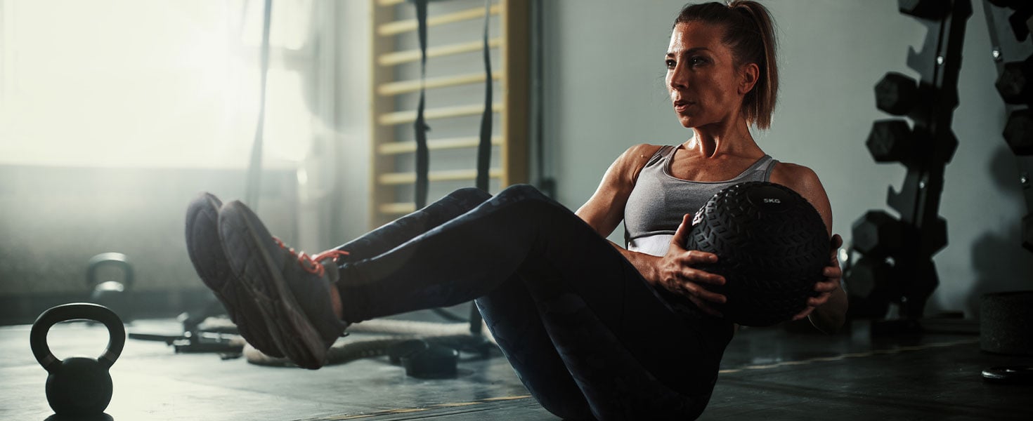 woman working out with weight ball and kettle bell weight
