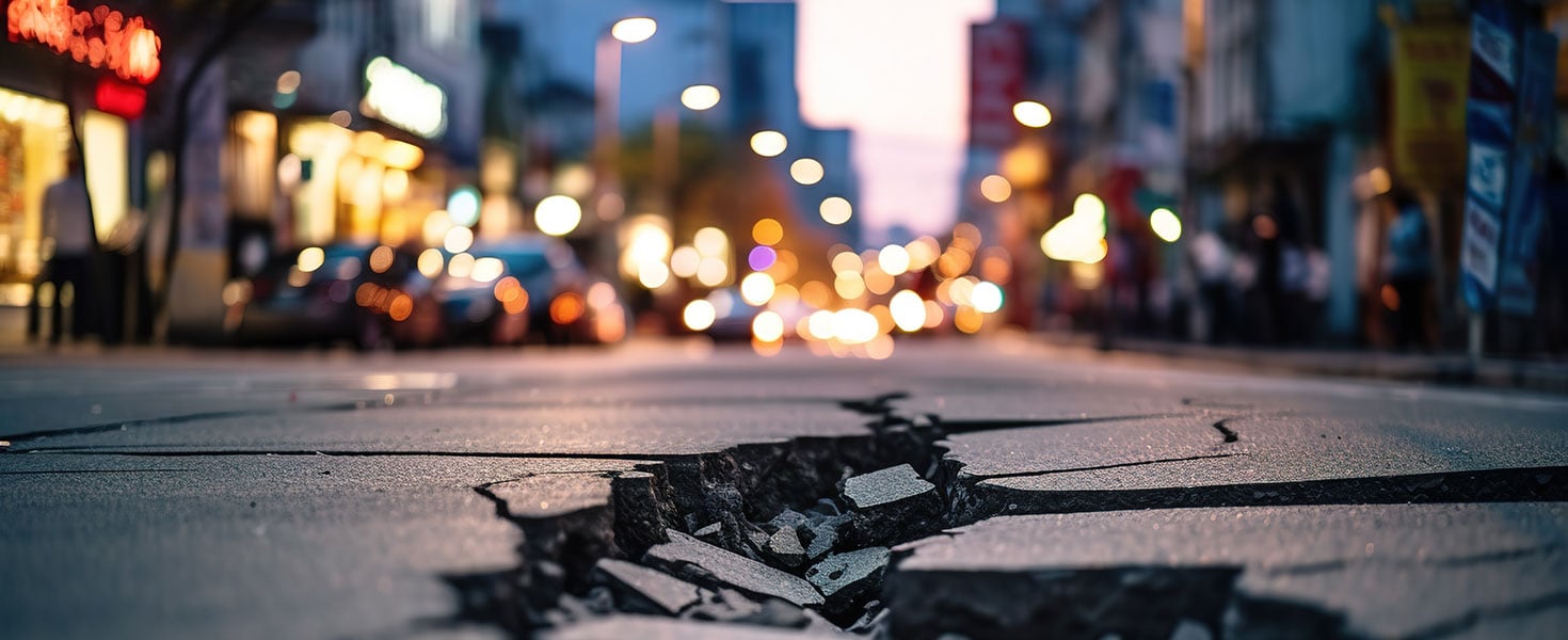 In a busy city street, there is a road with a long crack, depicting the effects of an earthquake. The background appears blurry By id512