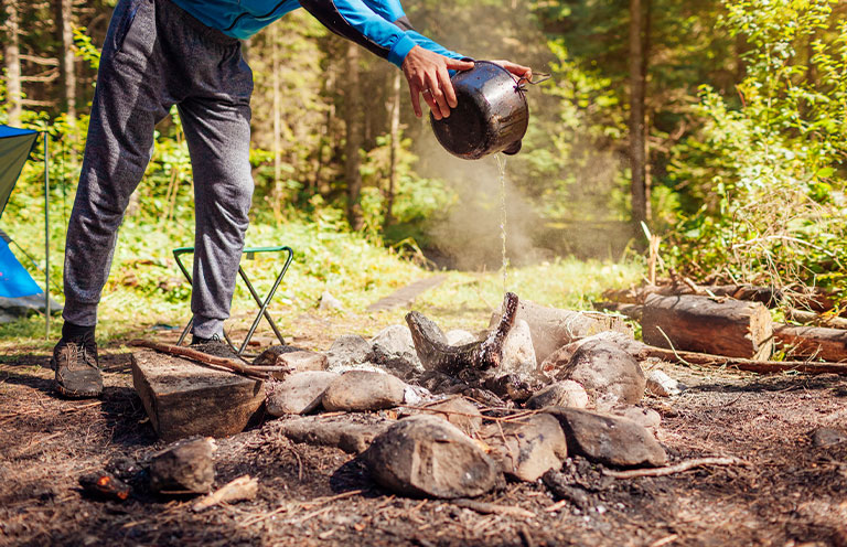 man pouring water over campire
