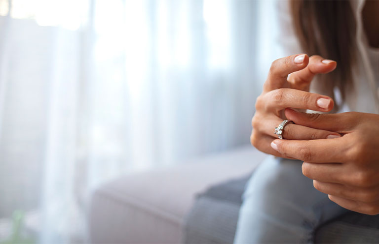 Sad girl looking at engagement ring sitting on a couch