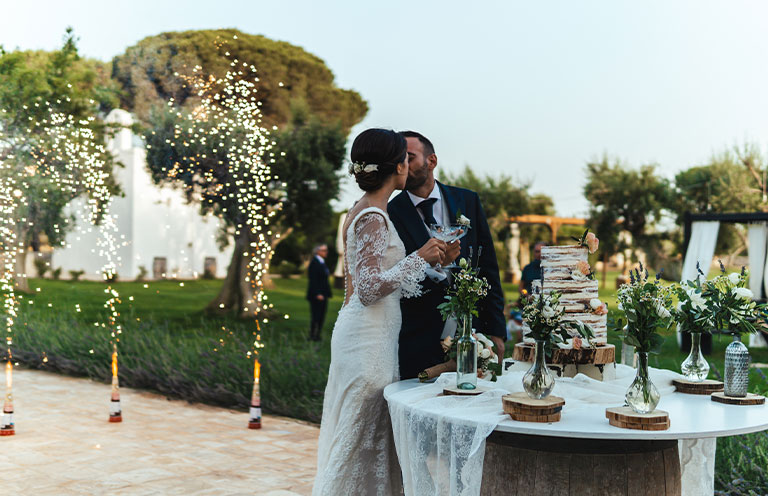 Cake cutting during wedding ceremony with fireworks in the background