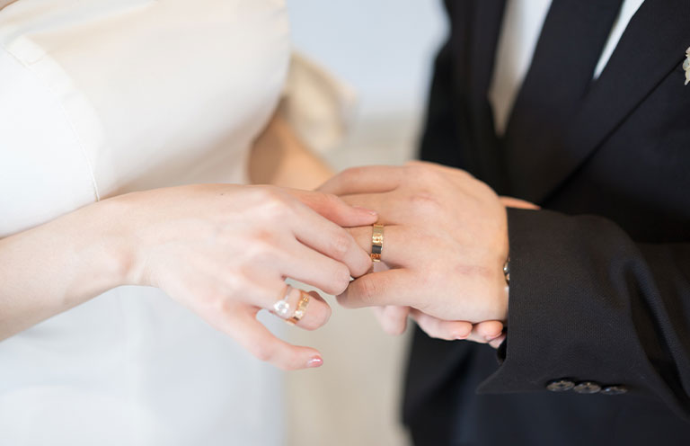 Bride putting on the wedding ring for the groom