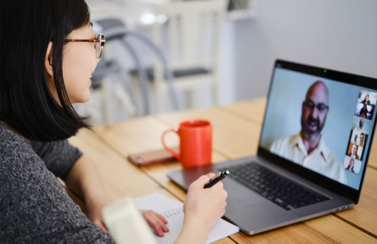 woman taking notes during video meeting