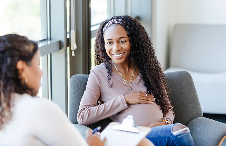 pregnant woman sitting and talking with another woman