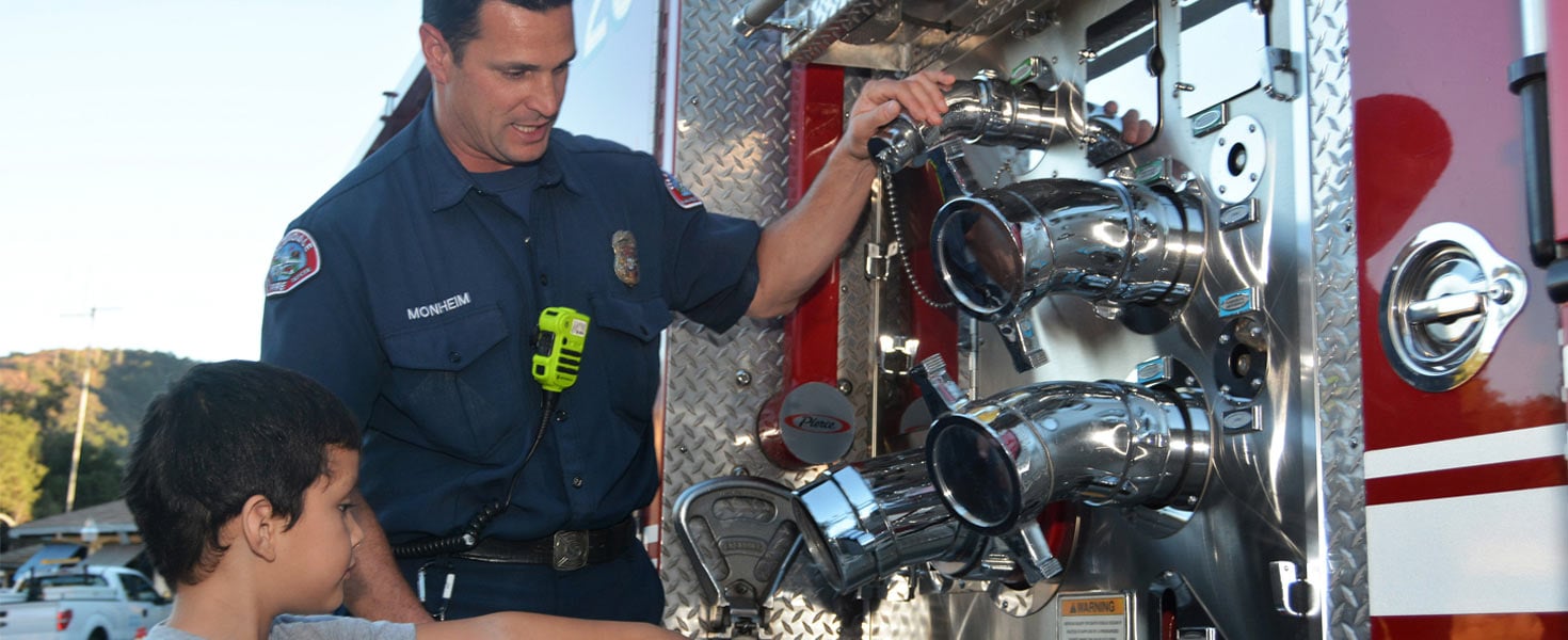 Fireman showing little boy parts of a firetruck