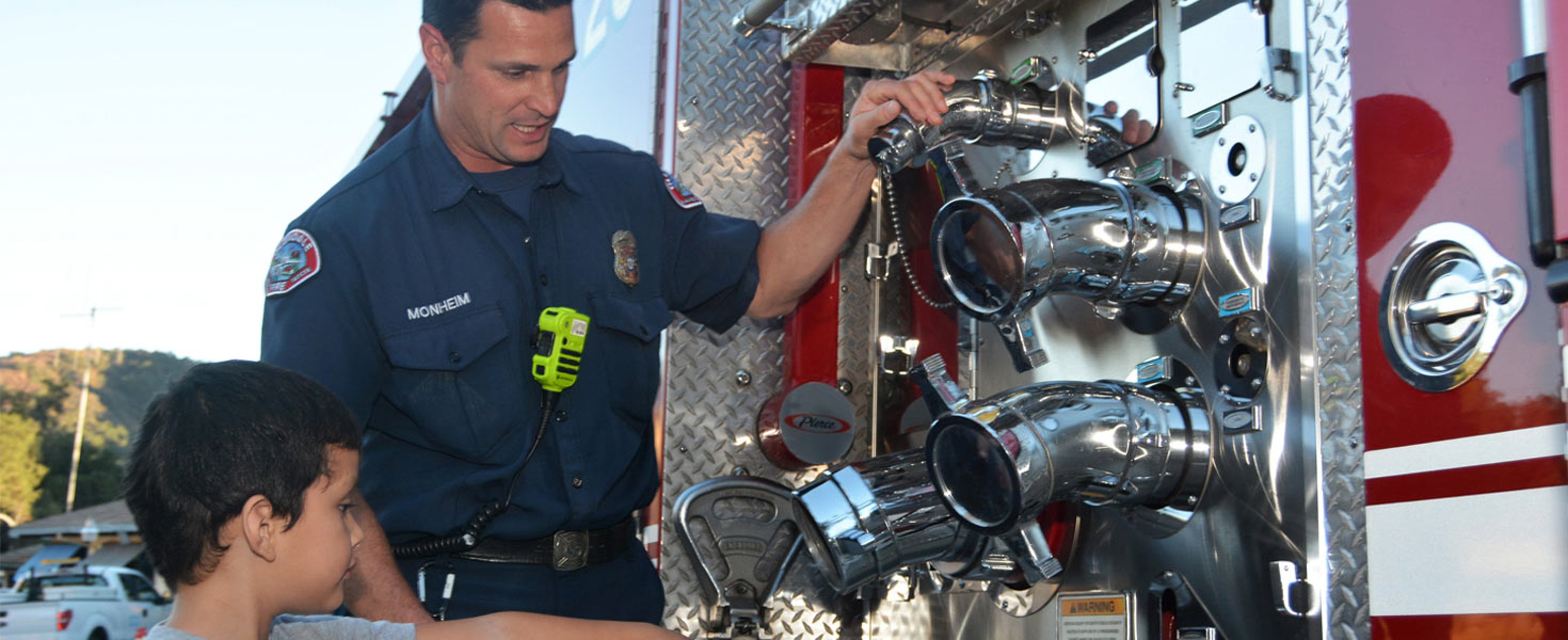 Fireman showing little boy parts of a firetruck