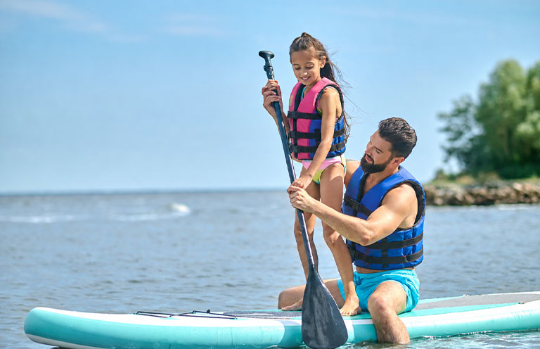 man holding little girl on a paddleboard