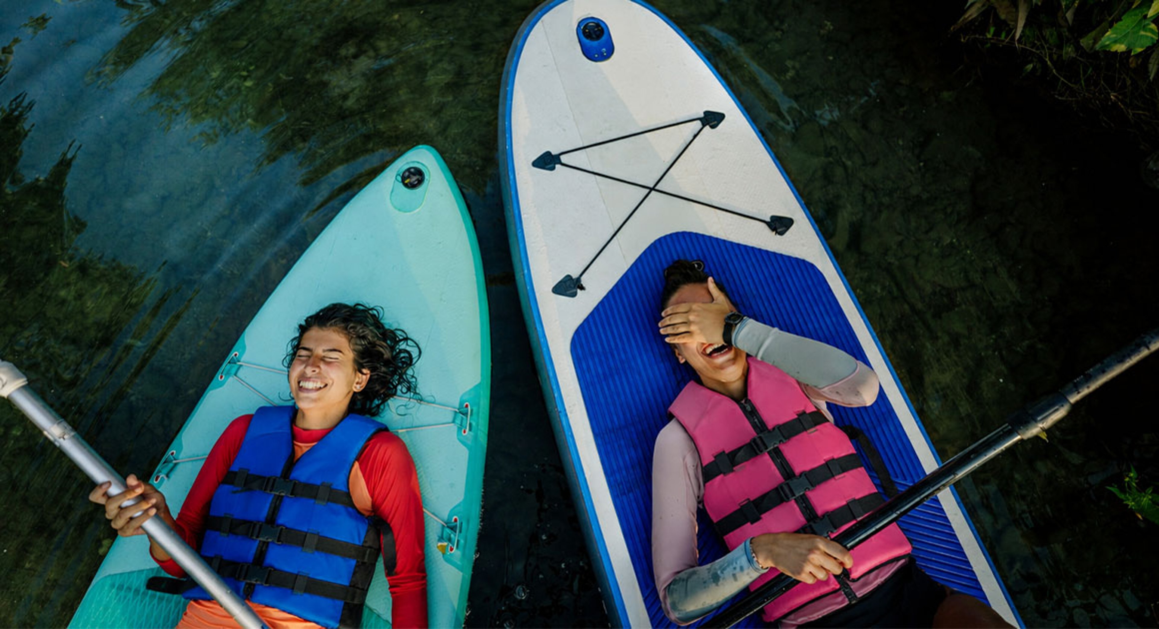 two girls laying on a paddleboard