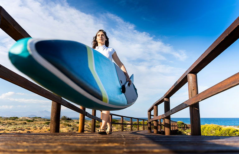 woman walking and holding paddleboard
