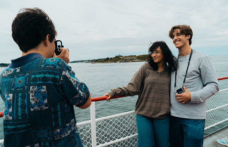 man taking photo on polaroid camera of man and woman