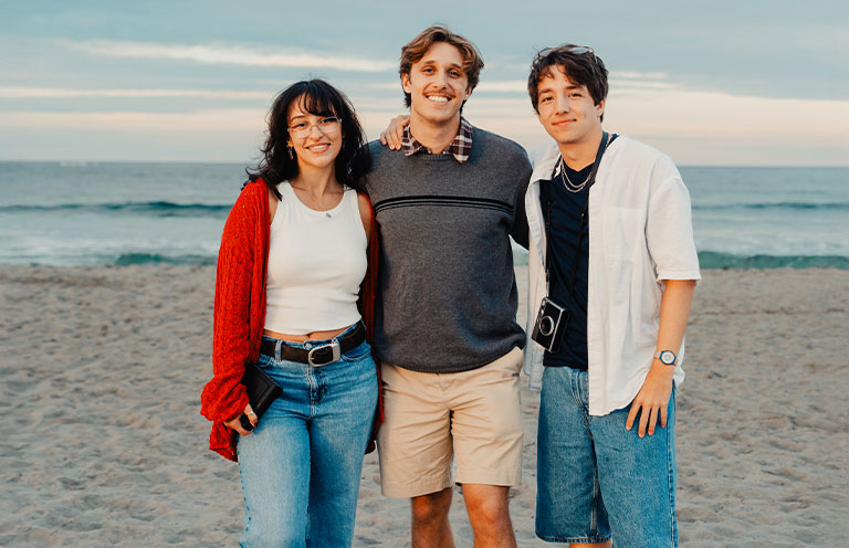 three friends pose at the beach