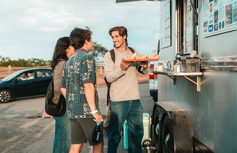 three friends getting lobster rolls from food truck