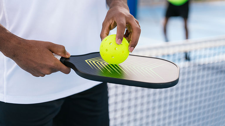 Close-up of pickleball paddle and ball in African American player's hand, outdoor game by Koldo_Studio