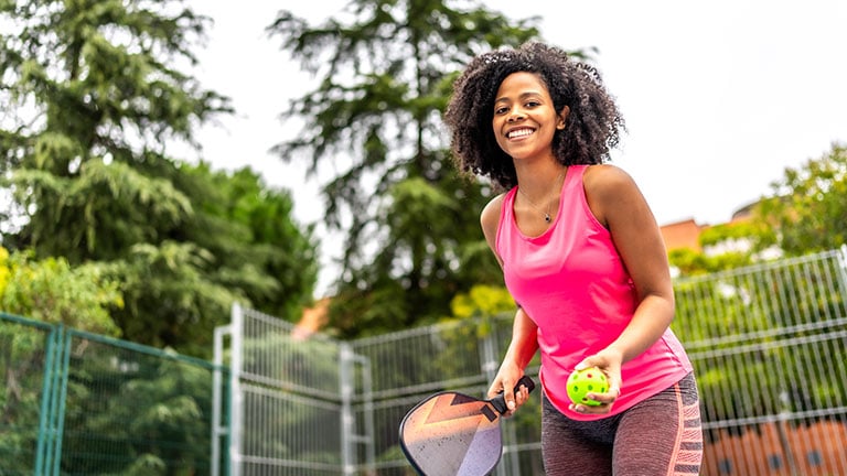 Happy female pickleball player about to serve at court by unai