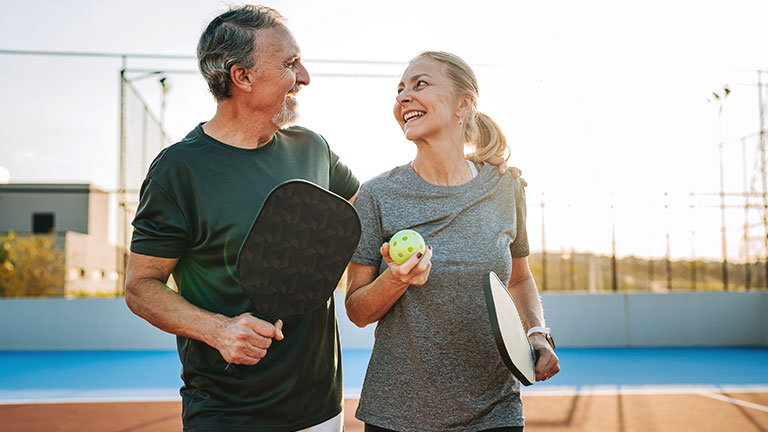 Mature, elderly couple play pickleball together; Credit:andreswd