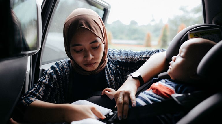 woman buckling baby into car seat