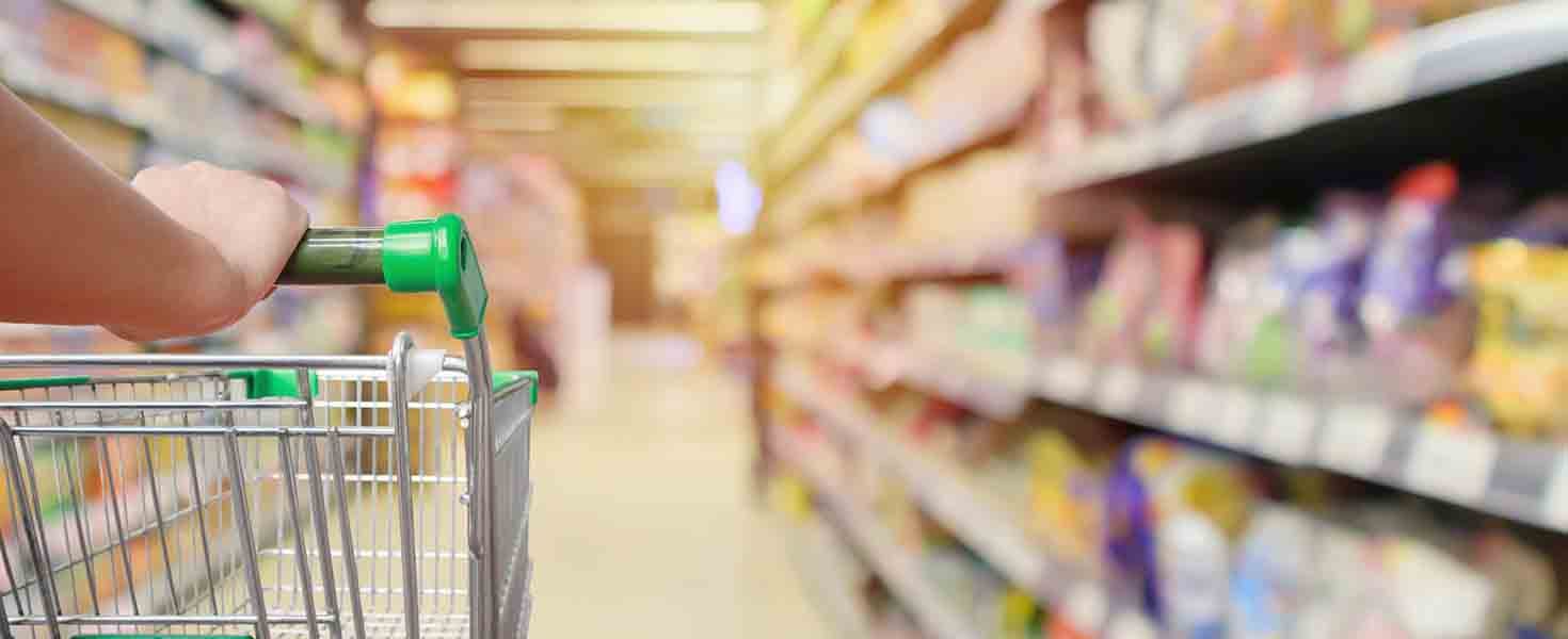Shopping cart in supermarket aisle with product shelves interior defocused blur background